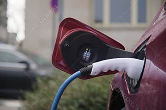 Closeup shot of the process of charging a red electric car with EV charger device in Jena, Germany