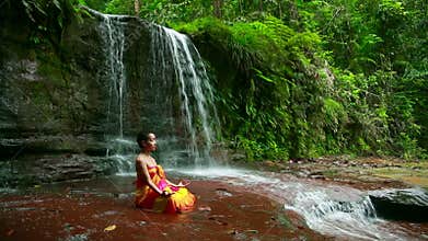 Meditating with Facial Painting in borneo rainforest waterfall