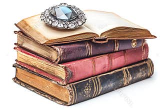 Antique books stacked with an open volume topped by a decorative brooch