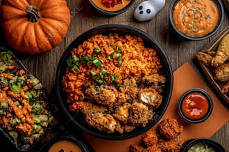 Pumpkins, spiders, ghosts, and a bunting flag garland are arranged in a flat lay composition on an orange background