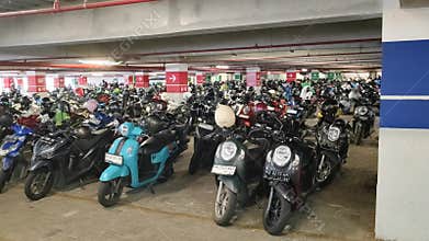 Motorcycles and scooters tightly arranged in an organized indoor parking area