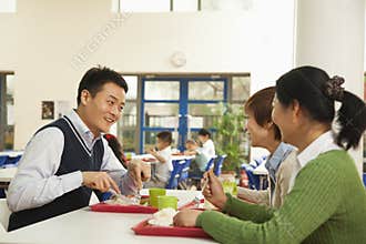 Teachers talking at lunch in school cafeteria