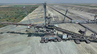 Flies over A heavy coal mining machine shovels coal with a bucket. Open pit. Green deal.