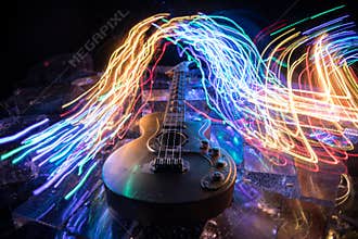 Music Concept: Guitar Miniature on a Dark Background with Vivid Light, Smoke, and Fire Effects. Golden electro guitar under a