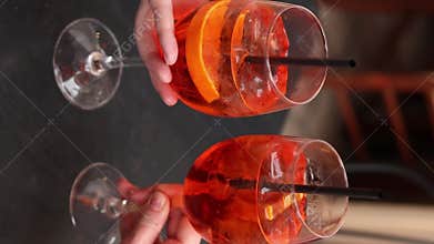 Two glasses with Aperol Spritz in the hands of girls