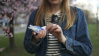Woman with allergies holding tissue under cherry blossoms in spring