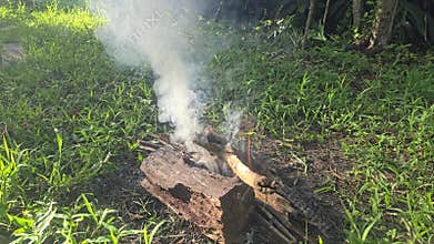 A small campfire is burning in a rural farmland.