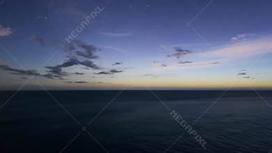 A solitary lighthouse stands tall on a rugged cliff as the sun sets, its beacon glowing softly