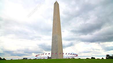 Tourists walk near the George Washington Monument in Washington, D.C. Green lawn, blue sky