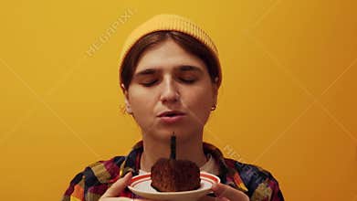 a woman or girl in vibrant orange clothes, happily about to blow out a candle on a birthday cake, appealing to both Generation Z