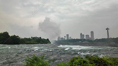 Niagara River rapids with foamy waves and city skyline