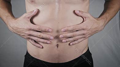 Man with Athletic Torso Touching His Abdomen in Pain