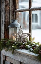 Christmas lantern and star decorating snowy window sill