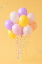 A vibrant cluster of pastel colored balloons floats upwards against a warm sunny backdrop creating a festive atmosphere