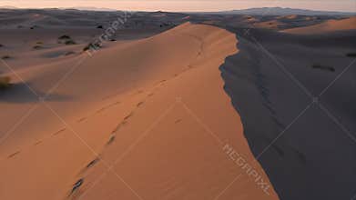 Dynamic Golden Hour Desert Dunes with Footprints and Distant Mountains