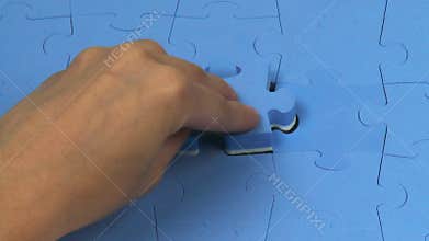 Hand placing the last piece on a puzzle
