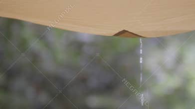 Raindrops falling from awning tarp tent at campsite.