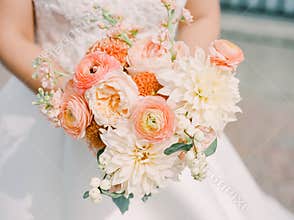 Beautiful bridal bouquet featuring peach and white flowers held by a bride outdoors during a wedding ceremony