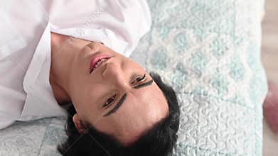 Top view of man flirting with camera while lying on bed.