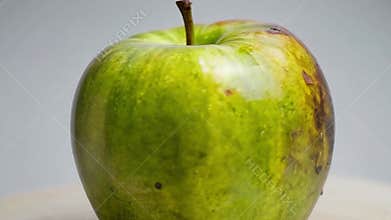 Zoom on a green apple that is rotten on one side