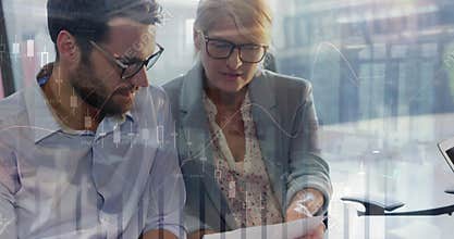 Man leaning toward document as financial chart overlays appearing while woman highlighting analysis
