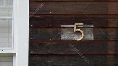 The number 5 on a rustic wood wall of a charming house showcases appealing aesthetics