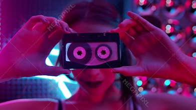 Young Club Girl Looking at Camera thru Retro Music Tape in Neon Color Lighting