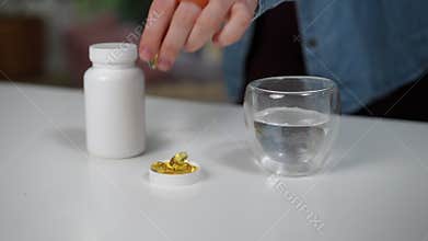 Hand selecting dietary supplements with water on the table