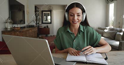 Woman wear headphones studying, making notes, doing assignment during videocall