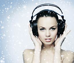 A young teenage girl listening to music in headphones on the snow