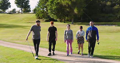 Golf players playing golf together, walking with clubs on a golf course on a sunny day