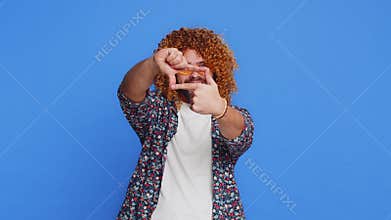 Man photographer gesturing picture frame with hands, looks through fingers focusing cropping image