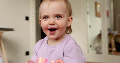 Adorable baby girl making funny faces and smiling at home