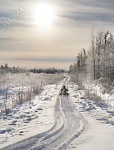 Snowmobile heading into sunlight.