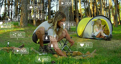 Male crouching arranging campfire wood in forest clearing with floating social media ads