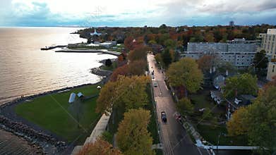 road surrounded by colorful trees, buildings, Time sculpture and Lake Ontario under cloudy sky