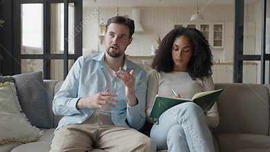 Couple On Couch, Man Explains While Woman Writes Notes In Notebook