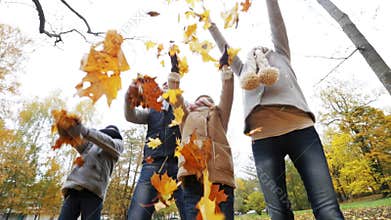 Happy family playing with autumn leaves in park