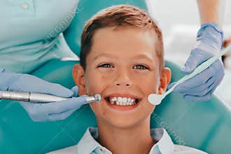 Cute boy smiling while teeth exam . Happy boy sitting in dentists chair and having check up teeth