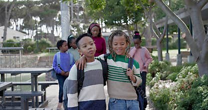 African American preteen boys walking in knits on campus, leading group with teacher and backpacks