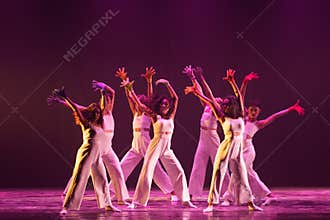 Synchronized Contemporary Dancers Raising Hands in Warm Stage Light