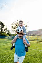 Dad and son having fun while practicing football outdoors.