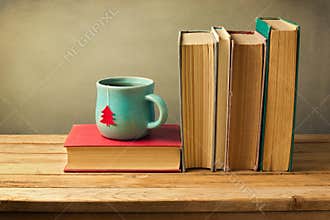 Vintage books and tea cup on wooden table. Christmas celebration.