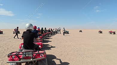 Convoy of Red Quad Bikes Crossing Desert During Safari Adventure