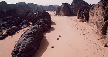 Aerial view of an off-road car convoy traveling through a sandy canyon in Algeria