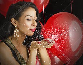 Beautiful young woman blowing confetti