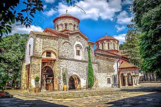 BULGARIA: Restored medieval stone monastery church surrounded by courtyard trees