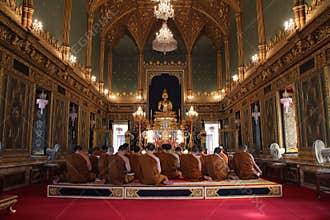 Buddhist monks are praying in the main hall of the Wat Ratchabophit, in Bangkok (Thailand)
