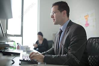 Serious devoted business man work in office on computer. Real economist business people, not models. Bank employees discussing