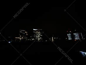 Dark night city skyline with illuminated office towers, glowing windows